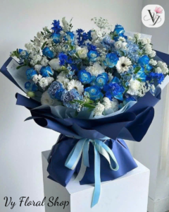 Sự Khác Nhau Giữa Hoa Tươi Chất Lượng Và Hoa Tươi Giá Rẻ: Bí Quyết Chọn Hoa 20/10 Tinh TếMỗi dịp Ngày Phụ nữ Việt Nam 20/10 đến gần, thị trường hoa tươi lại trở nên nhộn nhịp hơn bao giờ hết. Hàng loạt cửa hàng, xe hoa dạo cho đến các trang bán hàng online đồng loạt tung ra hàng ngàn mẫu hoa với mức giá chênh lệch đáng kể. Bạn có thể dễ dàng bắt gặp những bó hoa hồng rực rỡ chỉ vài chục ngàn đồng, nhưng cũng có những bó hoa cùng quy mô lại có giá lên đến hàng trăm hay cả triệu đồng.Vậy điều gì tạo nên sự chênh lệch mức giá ấy? Hoa tươi chất lượng và hoa tươi giá rẻ thực sự khác nhau ở điểm nào? Làm sao để không rơi vào cái bẫy "tiền mất tật mang" khi mua hoa quà tặng dịp lễ?Hãy cùng Vy Floral phân tích chuyên sâu về sự khác biệt này để bạn trở thành người tiêu dùng thông thái, lựa chọn được món quà đong đầy cảm xúc và trọn vẹn giá trị trong ngày 20/10 sắp tới!1. Nguồn Gốc Xuất Xứ & Quy Trình Tuyển Chọn HoaSự khác biệt cốt lõi đầu tiên giữa hoa tươi cao cấp và hoa tươi giá rẻ nằm ngay từ khâu canh tác, thu hoạch và phân loại nguồn hoa đầu vào.Hoa Tươi Chất Lượng CaoNguồn gốc rõ ràng: Thường được nhập trực tiếp từ các trang trại hoa nổi tiếng tại Đà Lạt (như Dalat Hasfarm) hoặc nhập khẩu nguyên cành từ Hà Lan, Ecuador, Nhật Bản, Kenya.Quy trình tuyển chọn nghiêm ngặt: Hoa được cắt cành đúng độ chín, cành to khỏe, lá xanh mướt, đài hoa chắc chắn, cánh hoa dày dặn và không hề bị dập nát hay sâu bệnh.Độ nở chuẩn xác: Hoa được chăm sóc để nở chuẩn phom dáng, màu sắc tươi tắn, chuẩn tông và giữ được độ tươi kéo dài từ 5 đến 7 ngày (thậm chí lâu hơn nếu chăm sóc đúng cách).Hoa Tươi Giá RẻNguồn gốc trôi nổi: Thường là hoa loại 2, loại 3, hoa tồn kho từ các dạt buôn hoặc hoa cắt cành quá lứa từ các nhà vườn nhỏ lẻ không đạt tiêu chuẩn xuất khẩu.Chất lượng kém đồng đều: Cành hoa thường yếu, mỏng, lá héo hoặc dập, đài hoa lỏng lẻo. Nhiều loại hoa bị ngắt bớt cánh dập bên ngoài khiến phom hoa bị nhỏ và mất cân đối.Hoa "ngậm hóa chất" hoặc hoa đông lạnh: Để giữ hoa không bị héo trong thời gian dài, một số nguồn hoa giá rẻ sử dụng thuốc bảo quản nồng độ cao hoặc trữ đông lạnh lâu ngày. Khi mang ra nhiệt độ thường, hoa nhanh chóng bị héo rút, thâm đen cánh chỉ sau vài giờ đồng hồ.2. Kỹ Thuật Bảo Quản & Xử Lý Cành HoaMột bông hoa dù đẹp đến đâu nhưng nếu không được xử lý đúng kỹ thuật ngay sau khi cắt cành thì cũng sẽ nhanh chóng tàn phai.Tại các shop hoa uy tín: Hoa sau khi nhập về sẽ được tuốt lá thừa, cắt gốc chéo 45 độ bằng kéo chuyên dụng, ngâm dung dịch dưỡng hoa chuẩn quốc tế và bảo quản trong phòng mát duy trì nhiệt độ từ 18 – 22°C. Quy trình này giúp cành hoa hút đủ nước, thân hoa cứng cáp và sẵn sàng nở rộ rực rỡ nhất khi đến tay người nhận.Tại các điểm bán hoa giá rẻ: Hoa thường bị bó thành từng bó lớn, ngâm trong các thùng nước đục, cắm trực tiếp ngoài trời chịu nắng gió và bụi bẩn. Việc thiếu quy trình dưỡng hoa chuẩn khiến các mạch dẫn nước bị tắc nghẽn, dẫn đến hiện tượng gục đầu, thối gốc chỉ sau nửa ngày sử dụng.3. Nghệ Thuật Cắm Hoa, Phụ Liệu & Bố Cục Thiết KếHoa tươi không chỉ là một sản phẩm nông nghiệp đơn thuần, mà khi trở thành quà tặng, nó là một tác phẩm nghệ thuật đong đầy tâm huyết của người thợ kim hoàn hoa (Florist).Tiêu chíHoa Tươi Chất Lượng (Tại Shop Uy Tín)Hoa Tươi Giá Rẻ (Trôi Nổi)Tay nghề FloristĐược đào tạo bài bản, hiểu rõ phối màu, bố cục, nhịp điệu và tỷ lệ vàng của bó hoa.Cắm theo lối mòn, bó chặt tay làm dập cánh hoa, thiếu tính sáng tạo.Phụ liệu gói hoaSử dụng giấy gói nhập khẩu cao cấp (giấy lụa, giấy mica, giấy xi măng Hàn Quốc), ruy băng lụa mềm mịn.Sử dụng giấy ni-lông bóng giá rẻ, dễ nhăn nheo, phụ liệu thô cứng làm giảm giá trị món quà.Cấu trúc & Bố cụcBố cục bay bổng, thoáng dáng, kết hợp hoa chính - hoa phụ - lá điểm hài hòa, tôn lên vẻ đẹp từng bông hoa.Dùng quá nhiều lá đệm giá rẻ để "ăn gian" kích thước, chèn ép làm hoa chính bị che khuất.Thông điệp & Thẩm mỹMẫu mã hiện đại, sang trọng, cá nhân hóa theo gu thẩm mỹ và thông điệp của người tặng.Mẫu mã đại trà, rập khuôn, thiếu điểm nhấn cảm xúc.4. Tác Hại Khi Mua Phải Hoa Tươi Giá Rẻ Dịp Lễ 20/10Nhằm tiết kiệm một khoản chi phí nhỏ, nhiều người quyết định chọn mua những bó hoa giá rẻ ngẫu nhiên trên đường hoặc từ các trang mạng thiếu uy tín. Tuy nhiên, quyết định này thường mang lại những trải nghiệm không mấy dễ chịu:Món quà bị giảm giá trị & Thiếu sự trân trọng: Một bó hoa héo úa, cánh hoa rụng rơi hay giấy gói nhăn nheo sẽ khiến người nhận (Mẹ, Vợ, Người yêu hay Đột ngột là Cấp trên, Đồng nghiệp) cảm thấy bạn chuẩn bị món quà một cách hời hợt, thiếu chỉn chu.Hoa tàn ngay trong ngày lễ: Rất nhiều trường hợp hoa mua buổi sáng rạng rỡ nhưng đến chiều tối đã gục đầu, thối gốc, làm hỏng hoàn toàn không khí vui tươi của buổi tiệc mừng 20/10.Rủi ro giao hàng trễ hẹn: Các điểm bán hoa giá rẻ thường không có quy trình vận chuyển chuyên nghiệp. Dịp lễ bận rộn dễ dẫn đến việc giao hoa trễ giờ, làm lỡ dở những kế hoạch tạo bất ngờ lãng mạn.5. Vy Floral – Địa Chỉ Đặt Hoa 20/10 Gò Vấp Hỏa Tốc Uy Tín & Chất LượngHiểu được rằng mỗi bó hoa gửi đi đều mang theo trọn vẹn niềm tin, tình cảm và sự trân trọng của người tặng, Vy Floral luôn kiên định với sứ mệnh mang đến những sản phẩm hoa tươi chất lượng cao nhất với mức giá hợp lý nhất.Nếu bạn đang tìm kiếm một địa chỉ uy tín để Đặt hoa 20/10 Gò Vấp hỏa tốc, đảm bảo hoa tươi mới 100%, thiết kế sang trọng và giao hàng chuẩn giờ, Vy Floral chính là sự lựa chọn hoàn hảo dành cho bạn!Vì Sao Khách Hàng Luôn Tin Tưởng Chọn Vy Floral?💐 100% Hoa Tươi Chọn Lọc Mỗi Ngày: Vy Floral chỉ nhập hoa tươi loại 1 từ các trang trại uy tín tại Đà Lạt và nguồn hoa nhập khẩu chất lượng. Cam kết nói KHÔNG với hoa đông lạnh, hoa dạt hay hoa tồn kho.🎨 Nghệ Thuật Cắm Hoa Hiện Đại: Đội ngũ Florist tâm huyết, liên tục cập nhật các xu hướng thiết kế hoa tươi Hàn Quốc, Châu Âu tinh tế. Từng bó hoa, lẵng hoa, hộp hoa bento hay kệ hoa đều được chăm chút tỉ mỉ từ màu sắc đến chất liệu giấy gói.🚀 Dịch Vụ Đặt Hoa 20/10 Gò Vấp Hỏa Tốc 1 - 2 Giờ: Đội ngũ giao hàng riêng biệt giúp vận chuyển hoa nhẹ nhàng, giữ nguyên phom dáng, không dập nát, giao tận tay người nhận nhanh chóng tại Gò Vấp và toàn bộ các quận huyện TP.HCM.📸 Hình Ảnh Thực Tế Chụp Tại Shop: Gửi hình ảnh sản phẩm hoàn thiện cho khách hàng kiểm tra và duyệt mẫu trước khi giao hàng.🎁 Trọn Bộ Quà Tặng Môi Trường: Tặng kèm thiệp chúc mừng thiết kế riêng, banner viết tay cá nhân hóa hoàn toàn miễn phí.Các Sản Phẩm Mũi Nhọn Dịp 20/10 Tại Vy Floral:🌹 Bó hoa hồng đỏ Hàn Quốc: Tình yêu nồng thắm, lãng mạn dành cho Vợ và Người yêu.🌊 Bó hoa tông xanh biển độc lạ: Sự thanh lịch, kiêu kỳ dành cho những cô nàng cá tính.🌺 Lẵng hoa Mẫu đơn & Cẩm tú cầu sang trọng: Lời biết ơn sâu sắc dành tặng Mẹ, Cô giáo và Cấp trên.🪴 Tiểu cảnh Sen đá phong thủy 15k (Mua 5 tặng 1): Món quà xanh bền bỉ, may mắn dành cho bạn bè, đồng nghiệp văn phòng.✨ Hoa sáp thơm cao cấp: Lưu giữ kỷ niệm vĩnh cửu theo thời gian.Thông Tin Liên Hệ & Đặt Hoa Nhanh Chóng:Tên cửa hàng: VY FLORALĐịa chỉ: 350 Nguyễn Văn Nghi, Phường 5, Quận Gò Vấp, TP. Hồ Chí MinhHotline / Zalo: 0775 190 086Slogan: Nâng niu từng khoảnh khắc👉 Đừng để những bó hoa giá rẻ làm giảm đi giá trị tình cảm của bạn trong ngày đặc biệt! Hãy liên hệ ngay Hotline/Zalo 0775 190 086 hoặc ghé thăm trực tiếp cửa hàng tại 350 Nguyễn Văn Nghi, Gò Vấp để trải nghiệm dịch vụ Đặt hoa 20/10 Gò Vấp hỏa tốc và trao gửi những đóa hoa tươi thắm, chỉn chu nhất đến người phụ nữ bạn yêu thương!